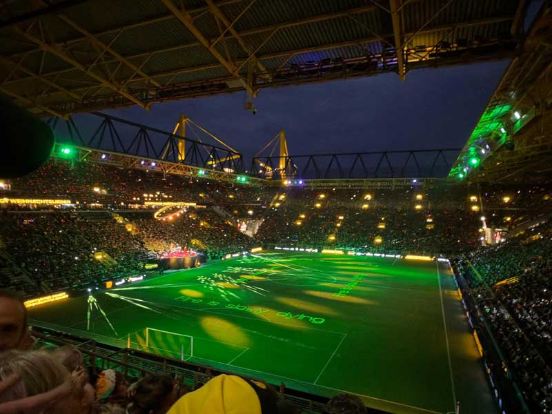 Beleuchtetes Fußballstadion bei Nacht mit vollem Publikum und Spielfeld